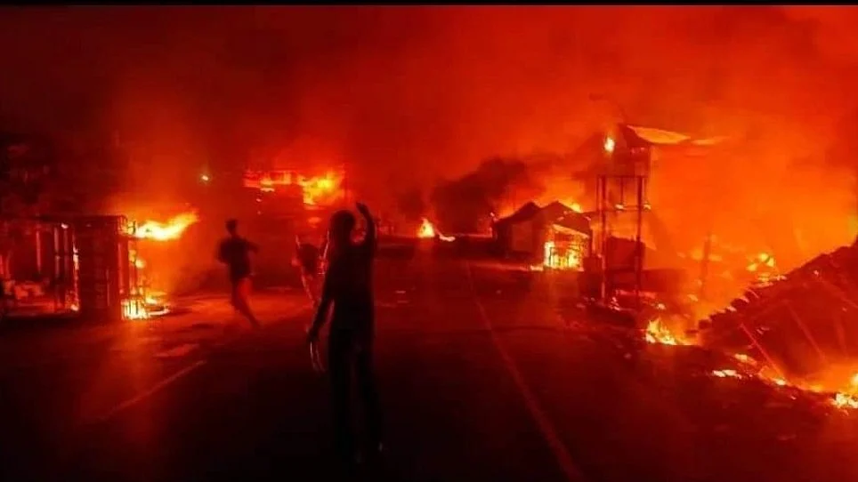 Buildings burning during the May 2023 outbreak of ethnic violence in Manipur, crowd watching in the foreground